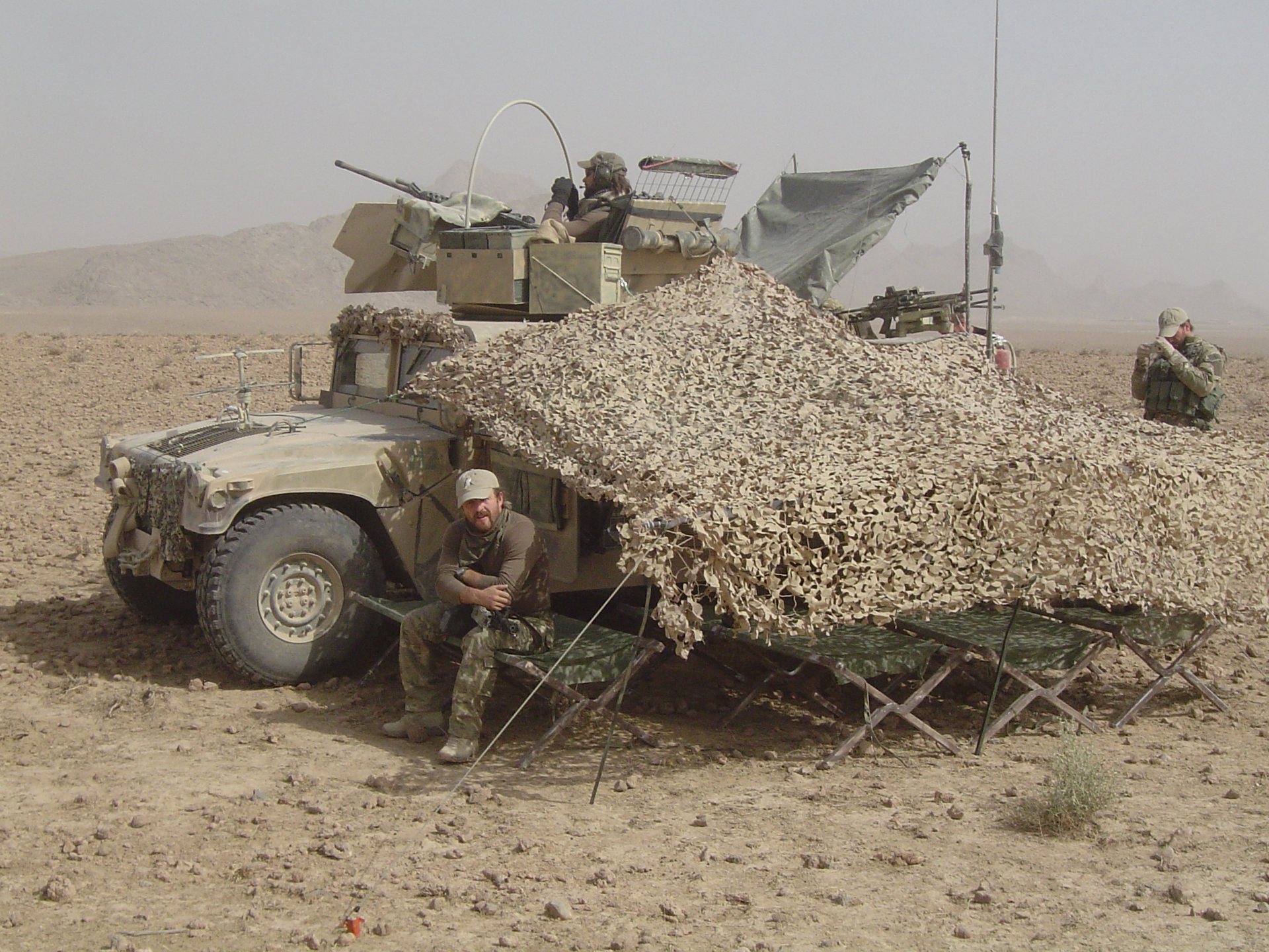 Humvee pod siatką maskującą w bazie polowej